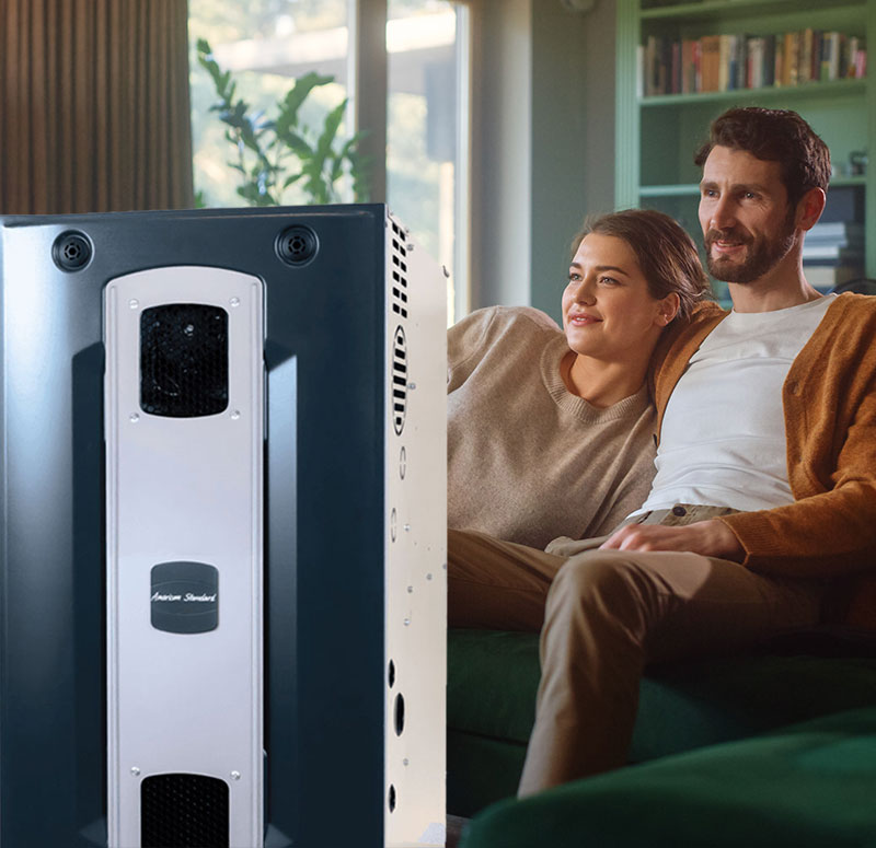 American Standard gas furnace with couple cuddling in their living room in the background